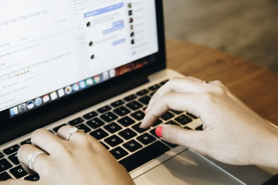 Close-up of hands typing on a laptop keyboard.